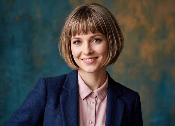 Frau mit einer rosa Bluse, einem dunkelblauen Blazer und einem Bob-Haarschnitt